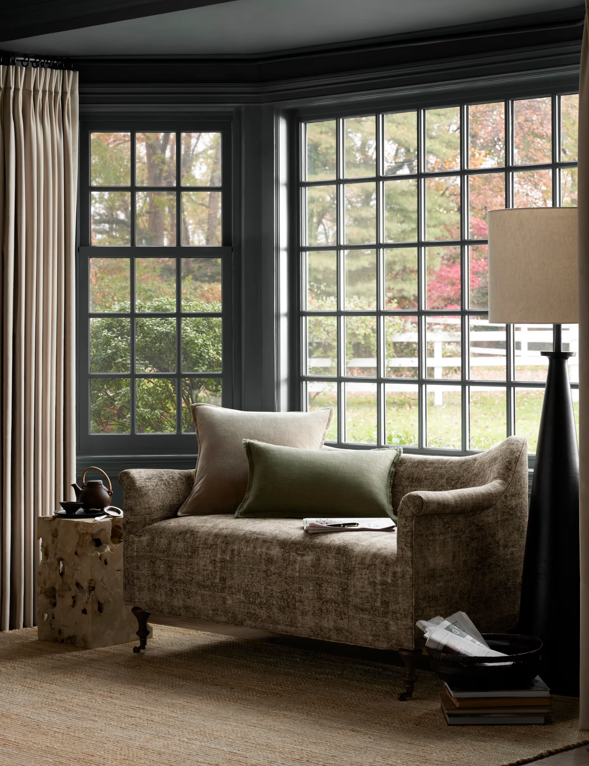 Patterned settee pictured in a charming, sunlit living room nook with large windowpanes