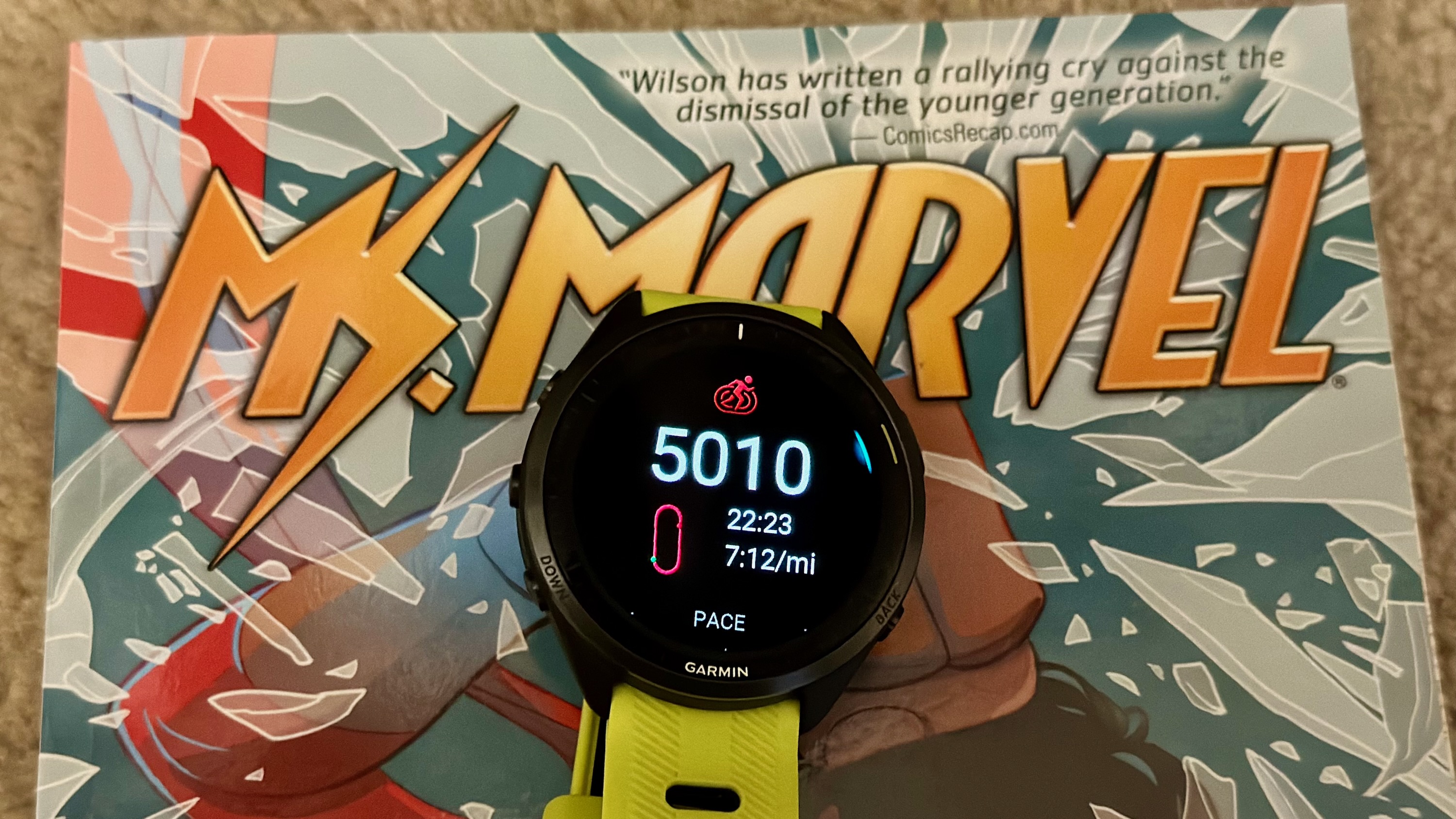 A Garmin Forerunner 965 sitting on top of a Ms. Marvel comic, showing a 5K time of 22:23.