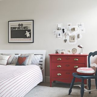 bedroom with white wall frame on wall grey flooring and white bed with striped cushions