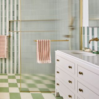 bathroom with green and white chequered floor tiles, stripey wall tiles, and double sink vanity unit