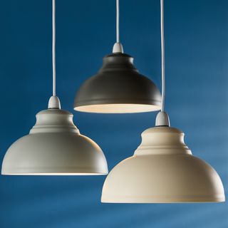 A trio of pendant light in assorted colours suspended in front of a blue background