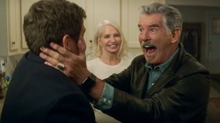Pierce Brosnan shows an expression of glee as Ellen Barkin watches him hold Adam Devine in The Out Laws.