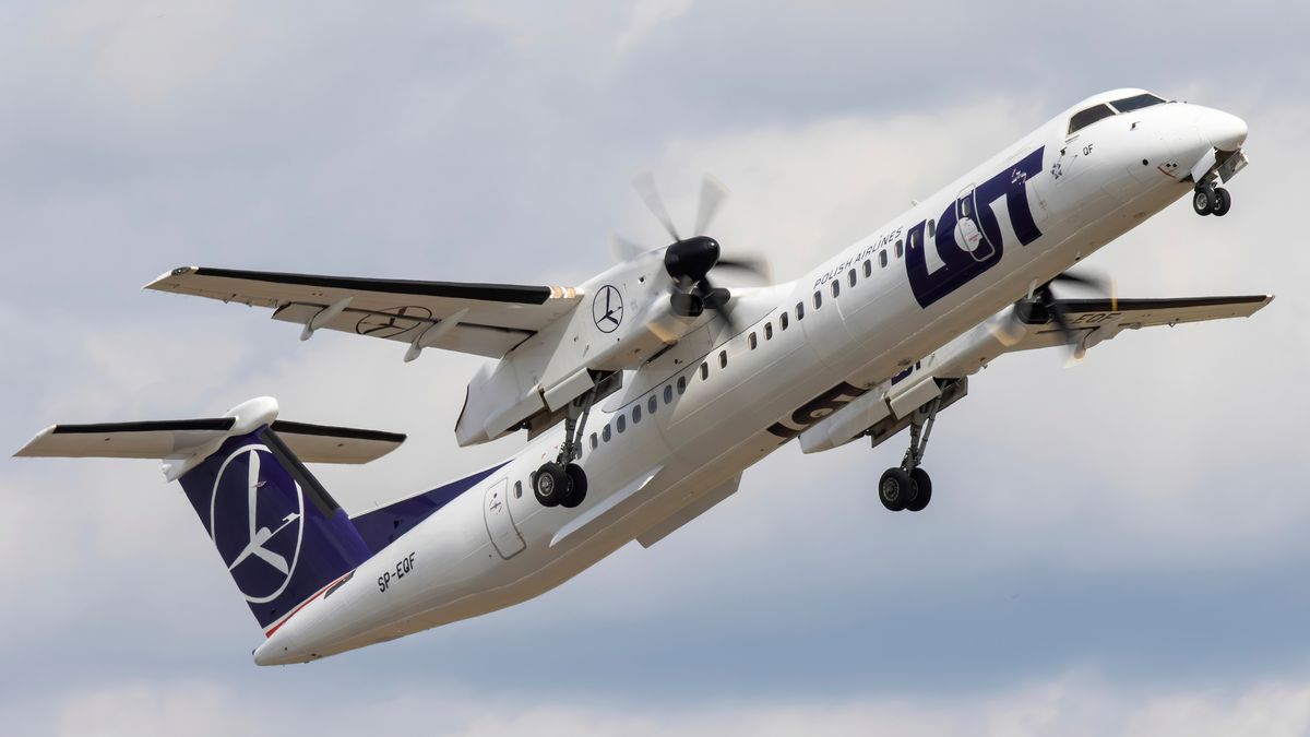 A plane manufactured by Bombardier flying against a cloudy blue sky 