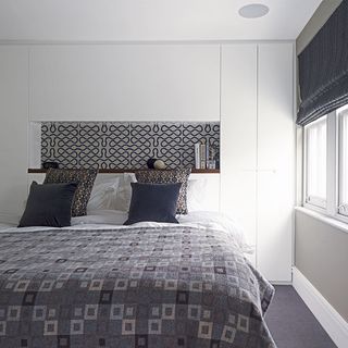 main bedroom with white wall and cushions on bed
