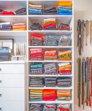 stacked and folded clothes on shelves in a white wardrobe