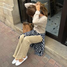 @annelauremais wearing a ballet flat outfit consisting of beige jeans, a checked shirt and white satin ballet flats.