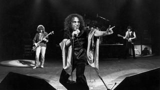 Photo of Ronnie DIO and BLACK SABBATH; L-R - Geezer Butler, Ronnie Dio (doing devil horns - manu cornuta), Tony Iommi at Gaumont.