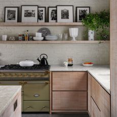 Modern kitchen range and fitted units with shelves and exposed painted brick wall and roof beams