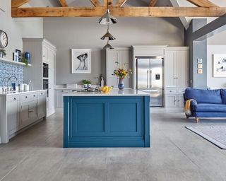 An open-plan kitchen with grey cabinetry, blue kitchen island with blue living room sofa