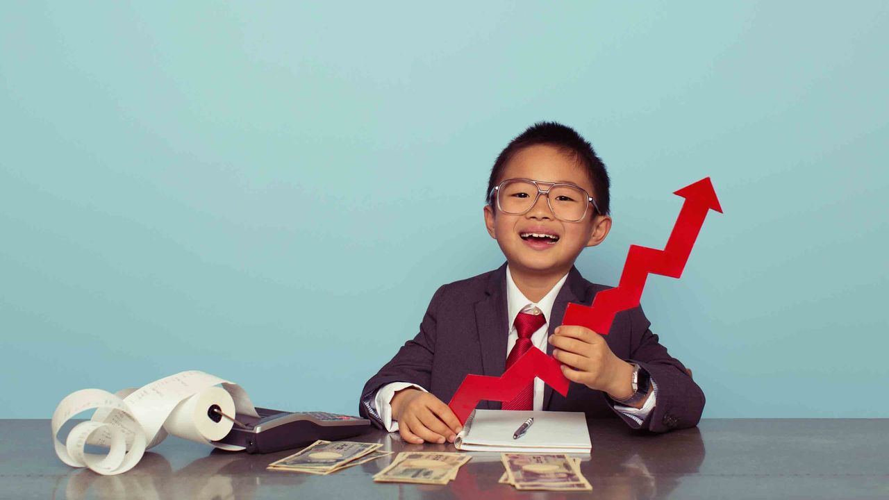 A child dressed up like a businessman holding a model of a stock chart arrow pointing up