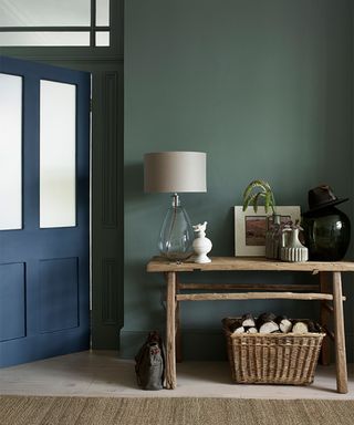 green painted hallway with wooden console and navy blue front door