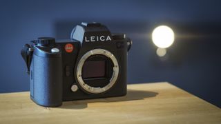 Leica SL3 camera on a wooden surface against a blue background