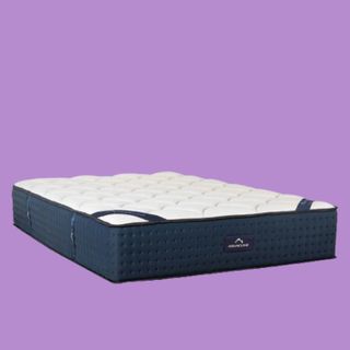 The navy and white DreamCloud Mattress, shown on a purple background, is the best mattress for couples due to high levels of motion isolation