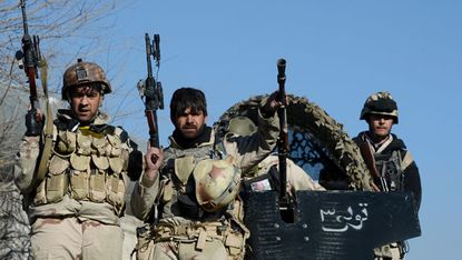 Afghan commandos sit on their vehicle after a clash with Taliban fighters