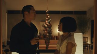Steven Yeun and Ali Wong face off in a dimly lit room with champagne in BEEF.