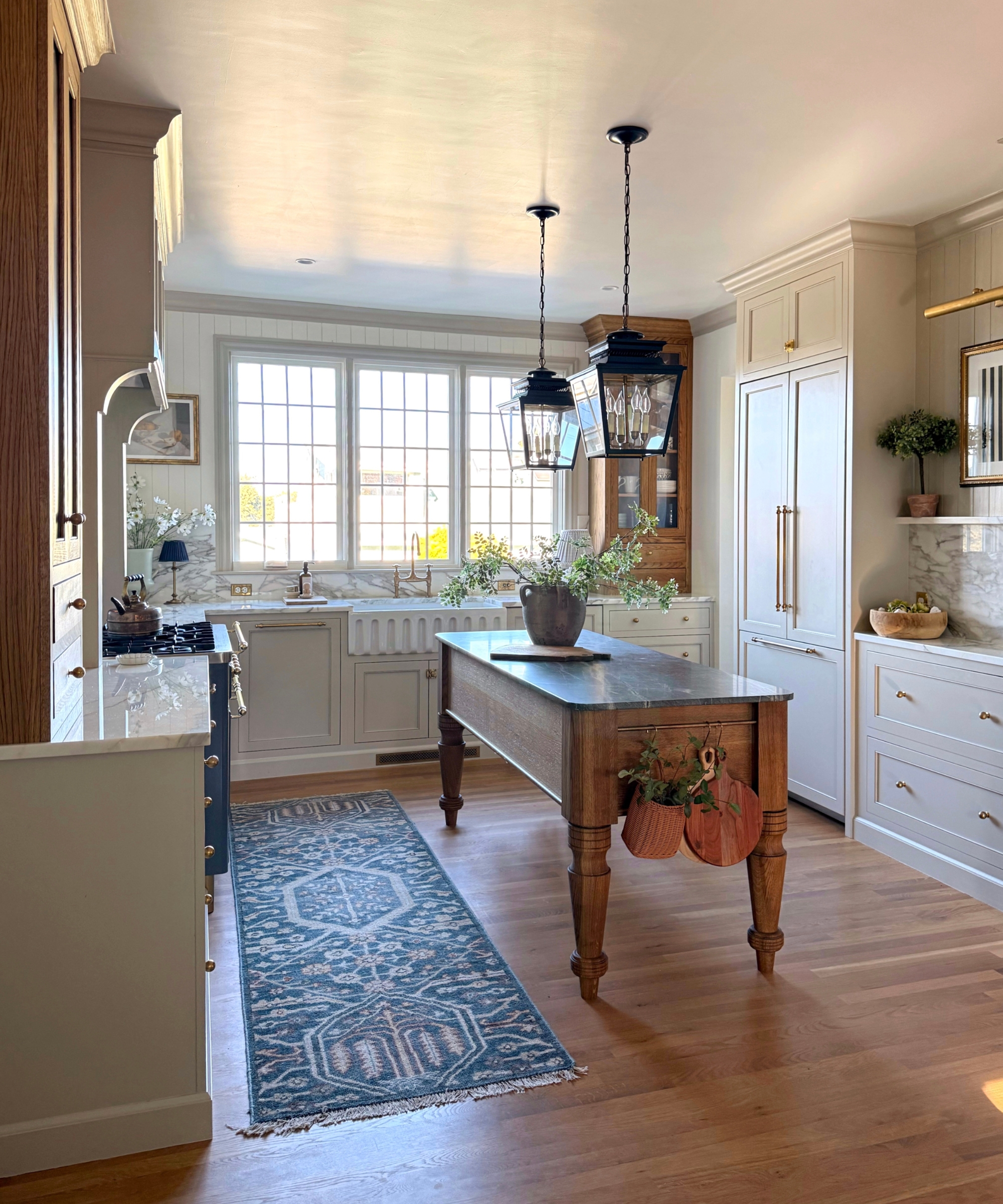 A U-shaped kitchen with cabinets painted in Sherwin-Williams' Alabaster and a freestanding vintage wood island