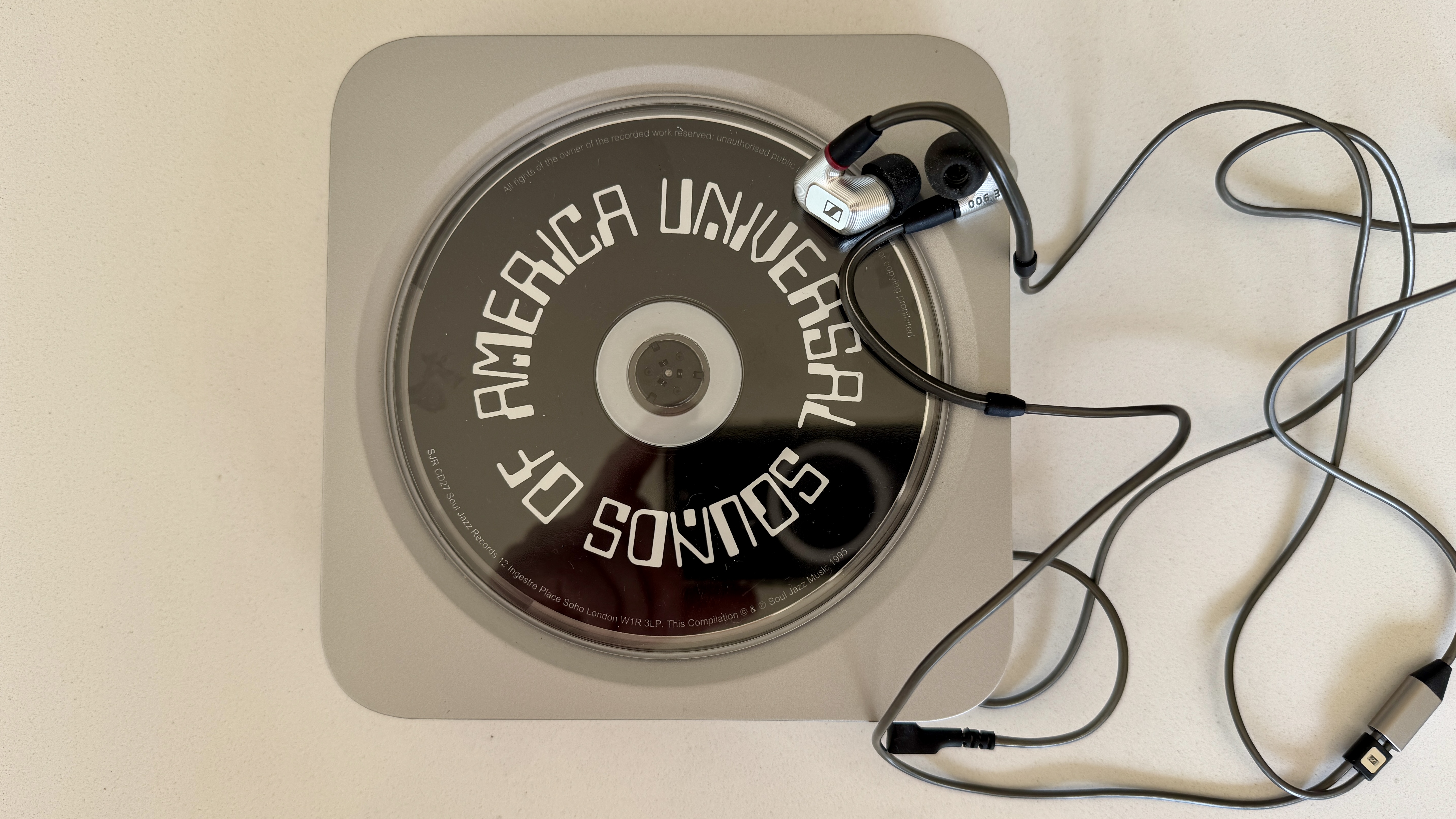 Top-down image of the Fosi Audio Merak CD player, with wired earphones coming out of the jack, on a white surface.