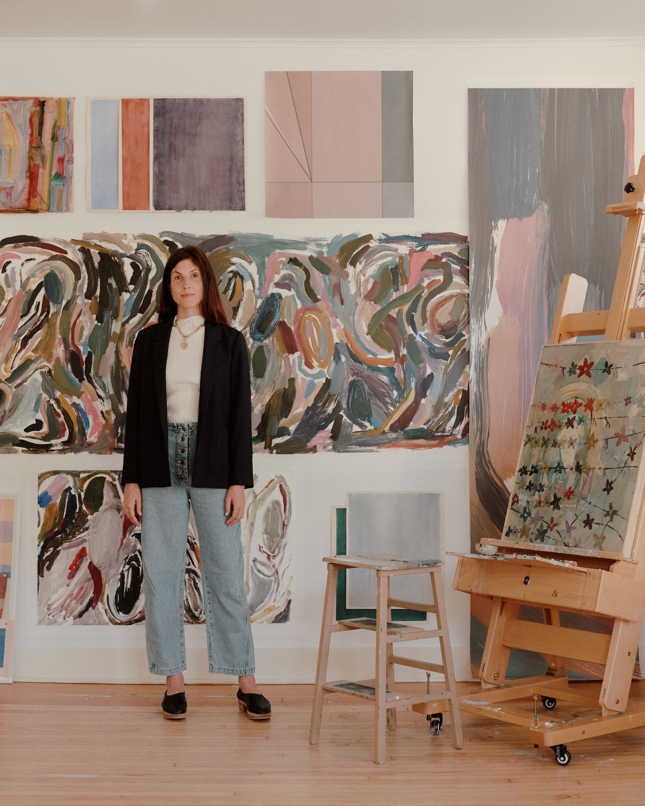 Image of Rachel Cope in front of art tests hanging on the wall in her upstate studio