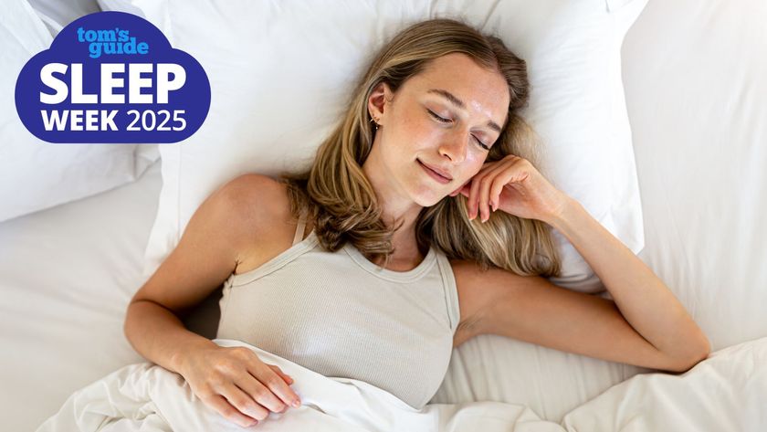 A woman sleeping on her back smiling in a brightly lit bedroom with a Tom&#039;s Guide Sleep Week 2025 logo in the top left corner