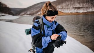Woman checking GPS watch while hiking in winter
