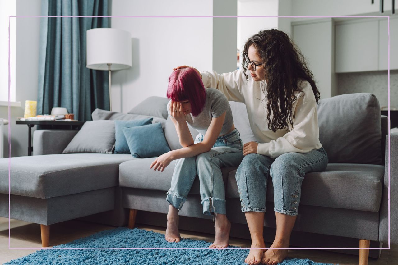 A mum comforting her teenage daughter while sat on a sofa