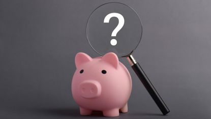 A piggy bank with a question mark over it's head in a magnifying glass