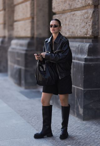 woman wearing moto boots, leather jacket, and black dress