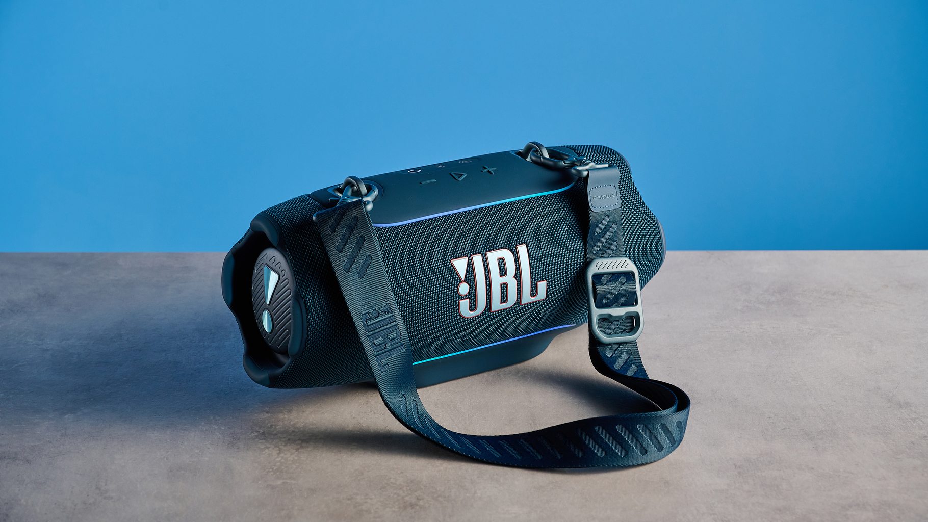 the JBL Xtreme 5 bluetooth speaker in blue shown with the rugged carry strap and buttons
