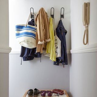 White and grey entrance hall, coats on hooks, wooden trunk