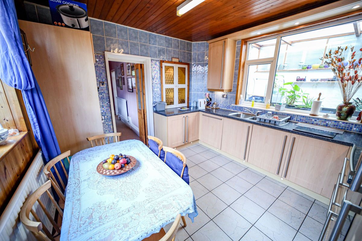 A kitchen with a small dining table and wooden panelled roofing