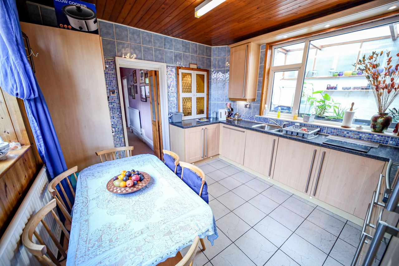 A kitchen with a small dining table and wooden panelled roofing