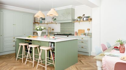 Green kitchen with large island and wooden floor