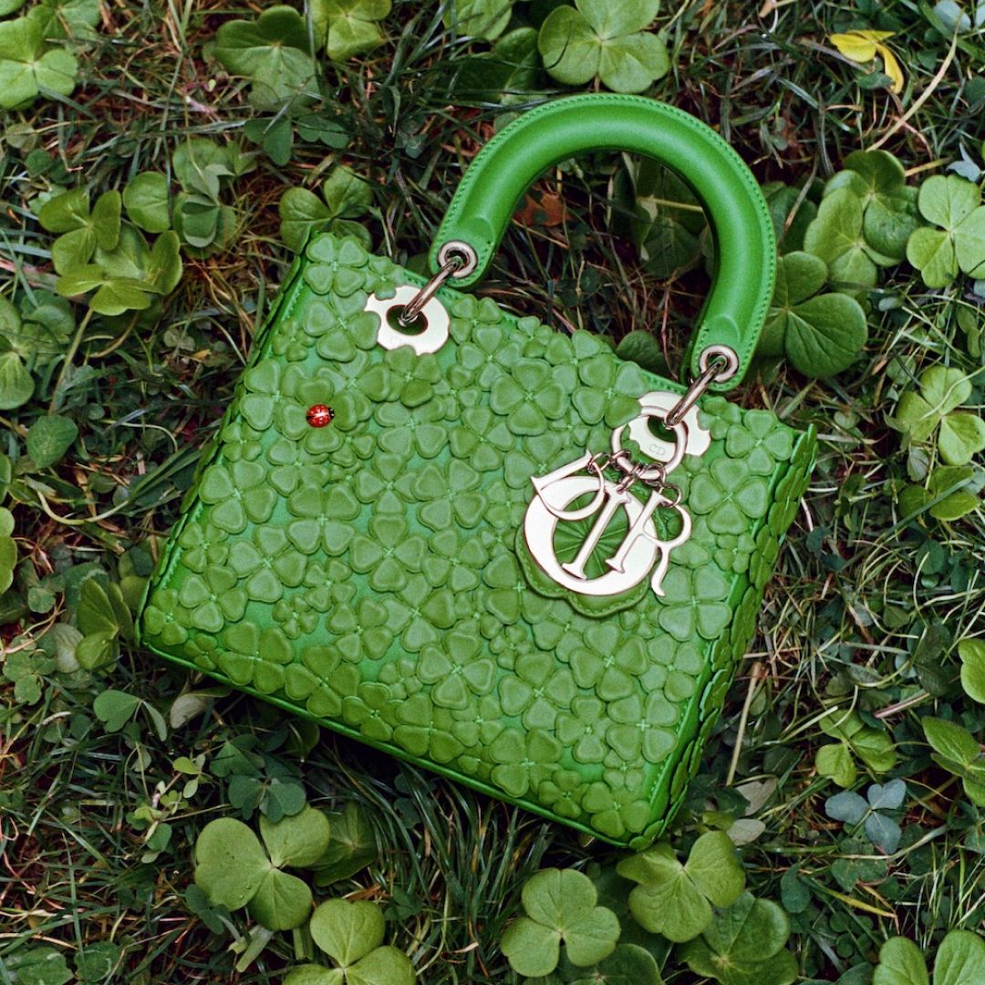 a lady dior bag covered in four leaf clovers laying on the ground