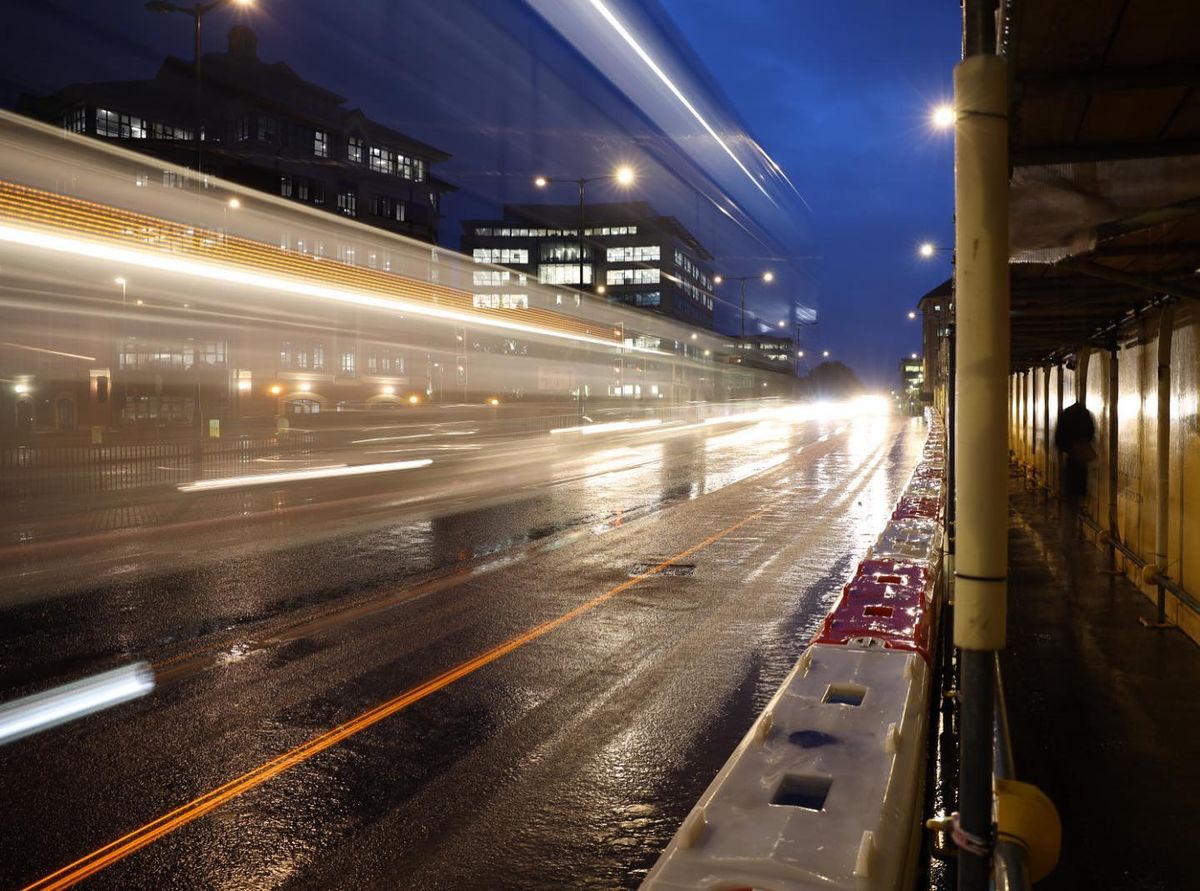 Long exposure shot of light trails from a bus, on a wet street scene at night, taken on a Canon RF 24-70mm f/2.8L IS USM lens