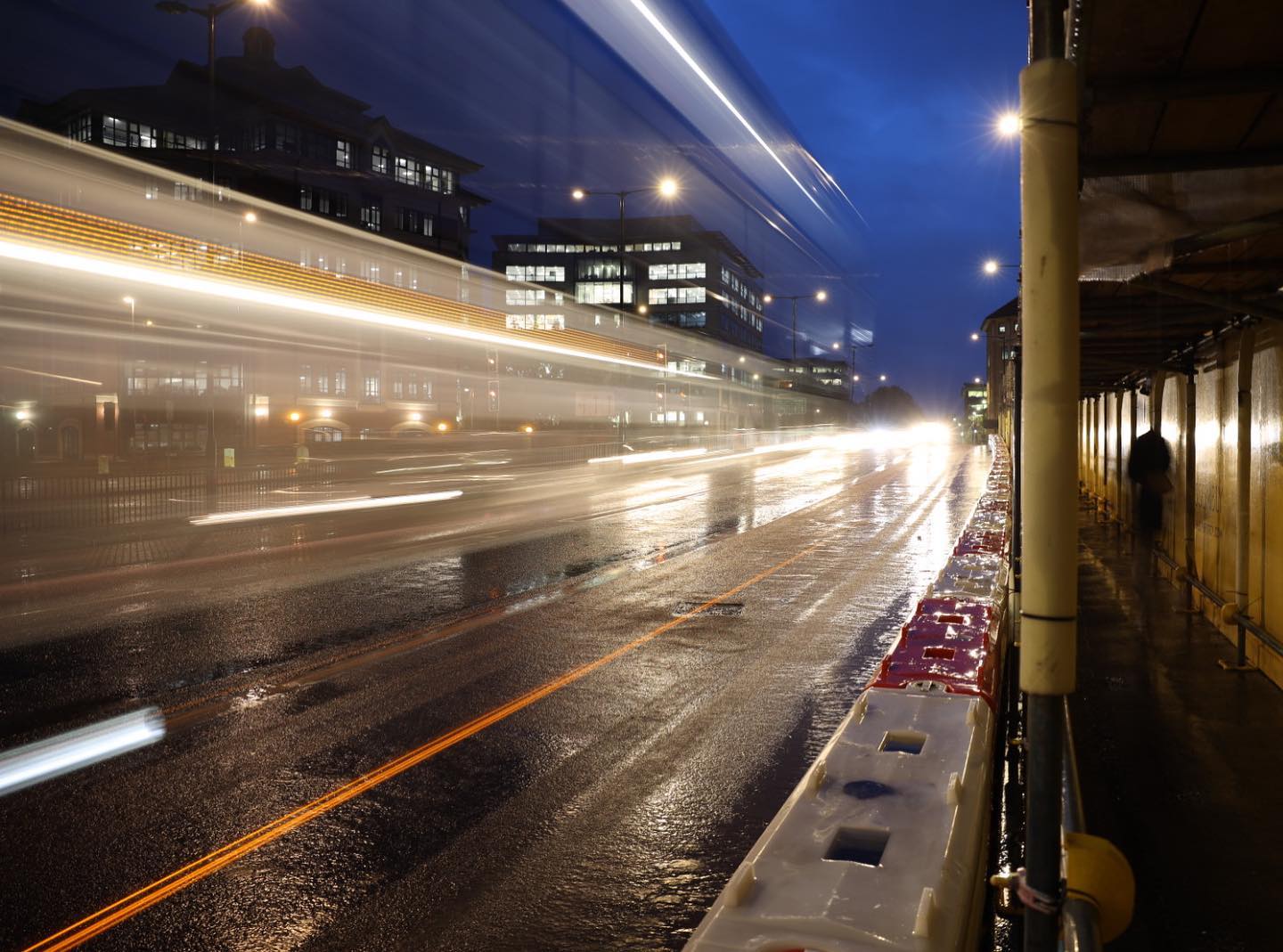 Long exposure shot of light trails from a bus, on a wet street scene at night, taken on a Canon RF 24-70mm f/2.8L IS USM lens