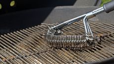 A metal grill brush cleaning a grill