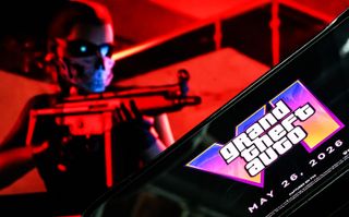 LONDON, ENGLAND - MAY 06: In this photo illustration, a phone displaying the Grant Theft Auto VI logo and new release date is shown in front of a screen displaying the second official trailer for the game, on May 06, 2025 in London, England. Last week, Rockstar Games, developer of the Grand Theft Auto franchise, announced the game had been pushed back to May of next year. (Photo by Leon Neal/Getty Images)