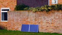 solar panels on floor against brick wall outside house