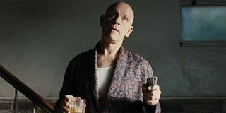 John Malkovich holding a drink and a gun in Burn After Reading