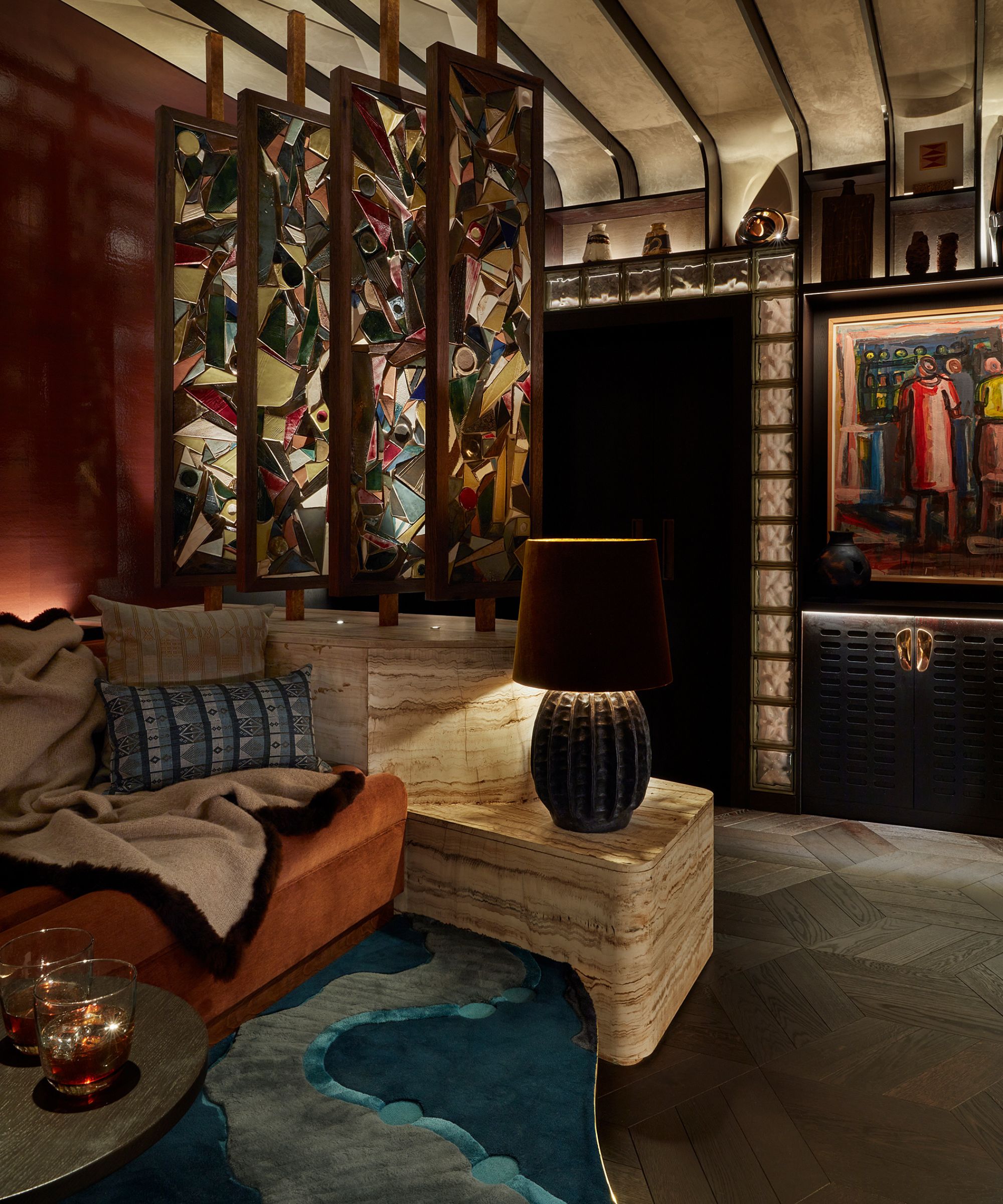 A moody media room with an orange sofa and a black lamp