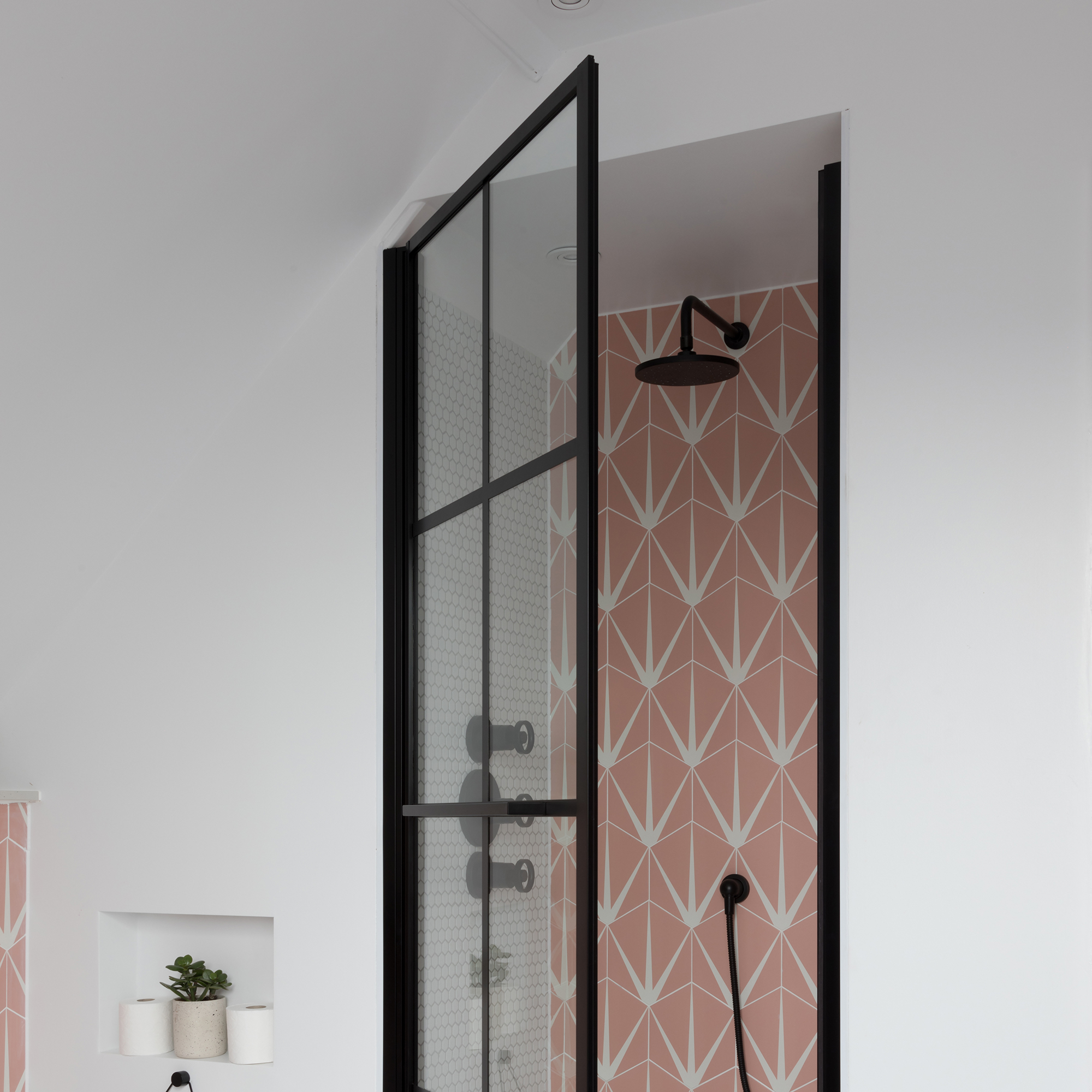Niche shower with black-framed door and pink geometric tile wall