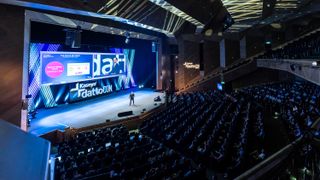 A wide angle photo of a conference hall showing Kaseya CEO Fred Voccola on stage speaking to an audience