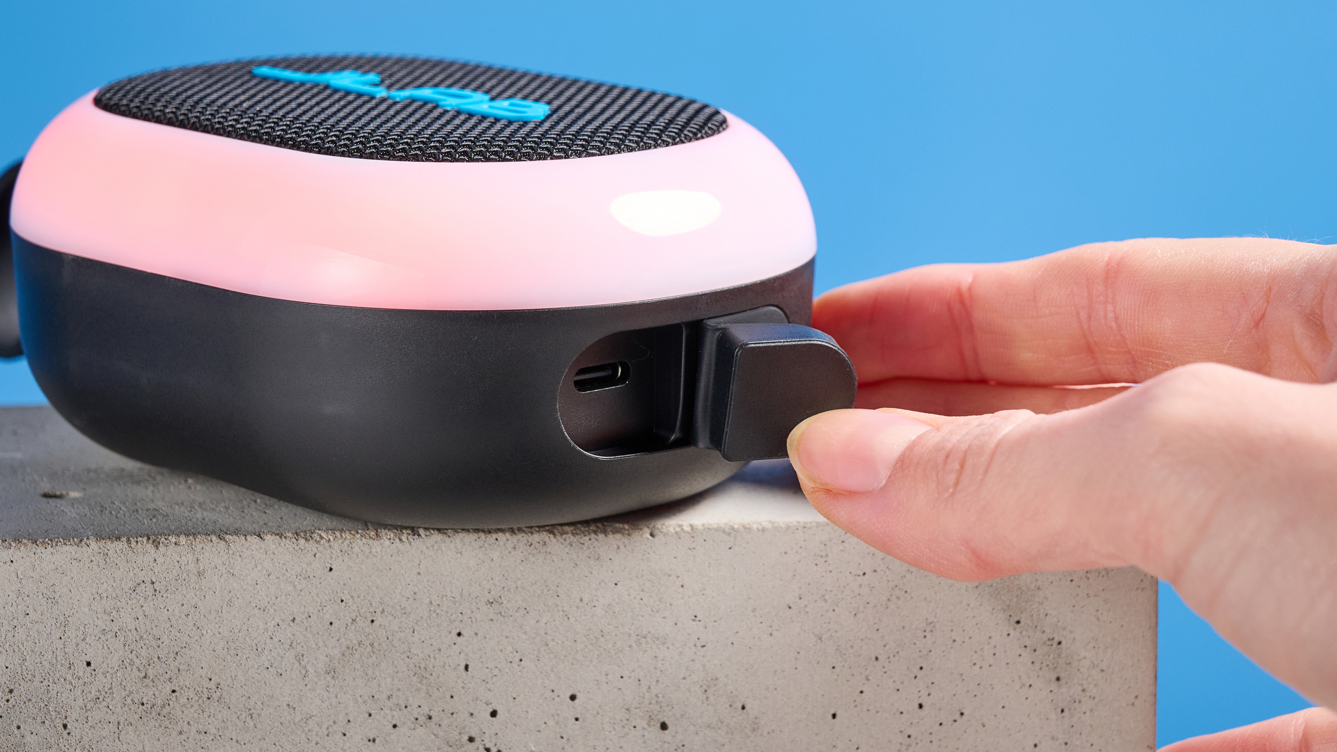 JLab Pop Party portable Bluetooth speaker with RGB lighting photographed on a blue background.