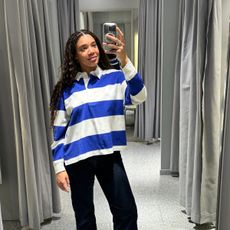 Imani-Nia Francis-Tsolakis in a blue and white Arket polo top dark blue jeans and biker boots.