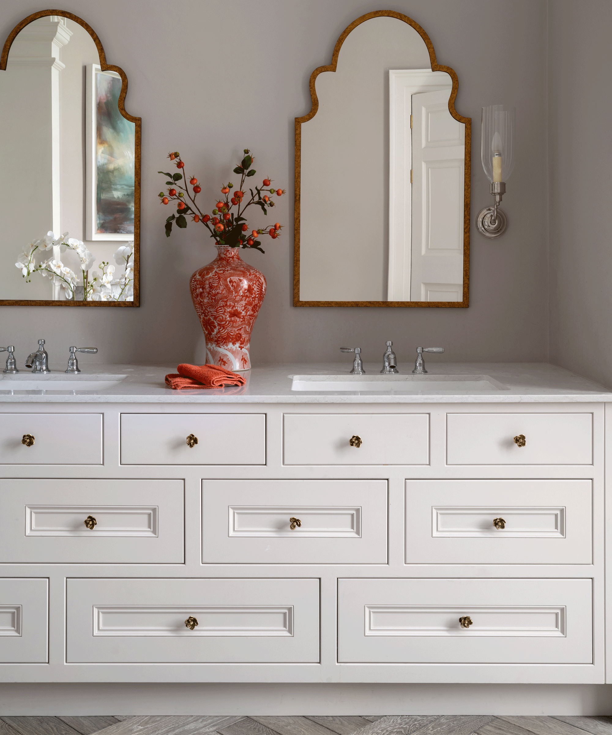 A bespoke white bathroom vanity unit with multiple storage drawers and a red vase sat on top