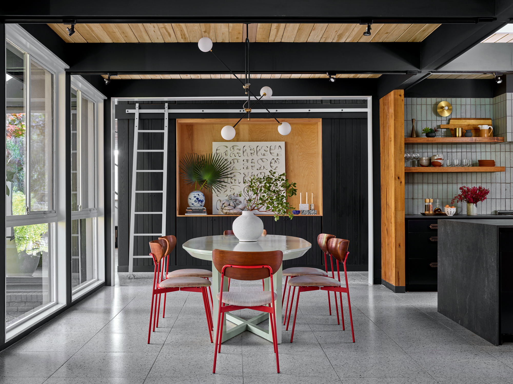 a black ply kitchen with a dining table and a ladder