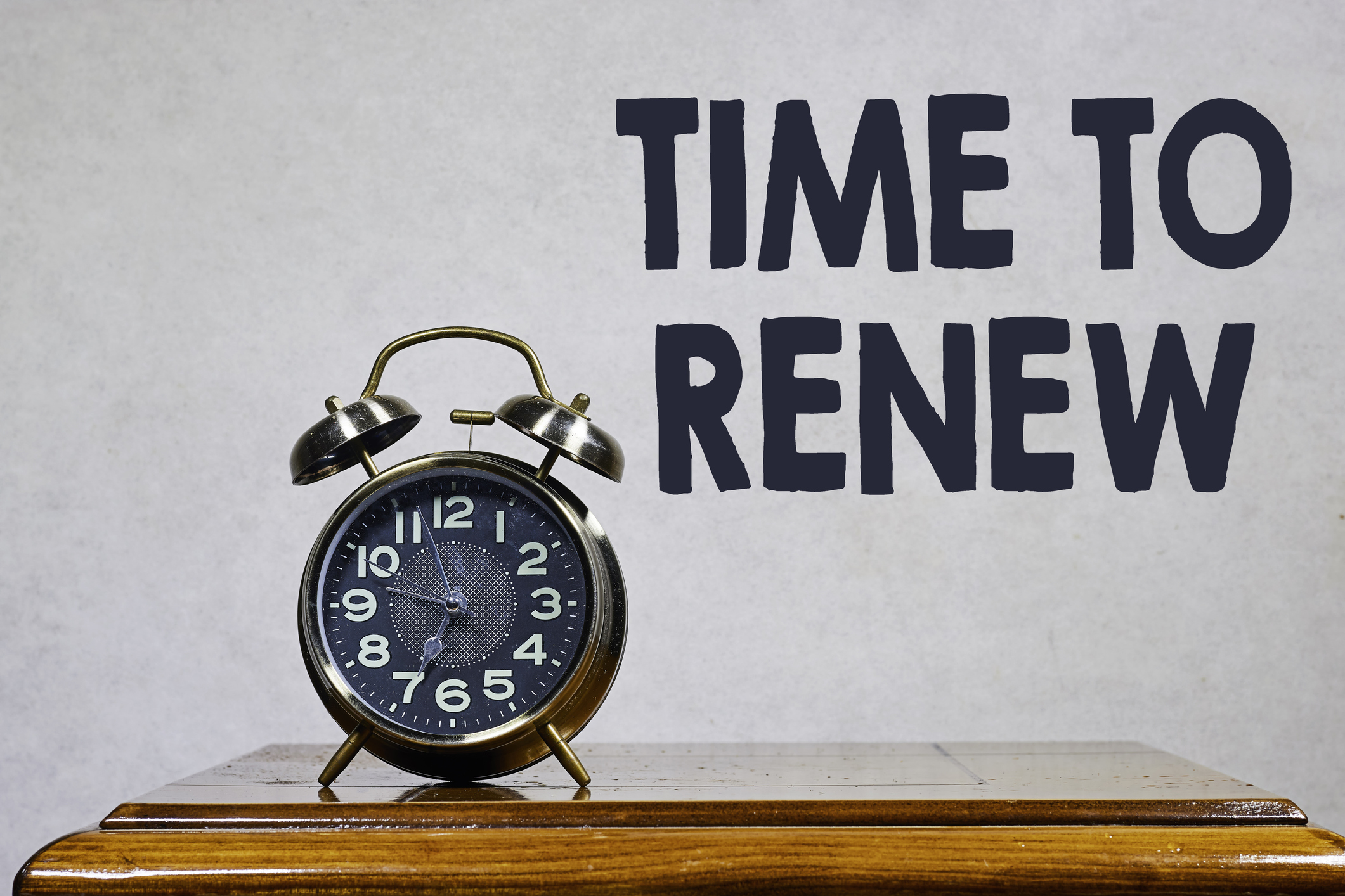 Time To Renew: Vintage Alarm Clock On Wooden Table With Bold Message On Wall