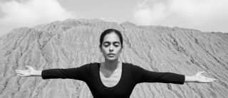 woman extending her arms in front of hill of sand