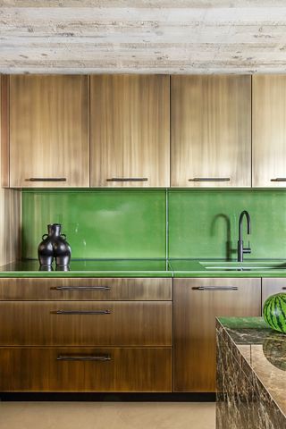 a brass textured kitchen with green lava stone counters and backsplash