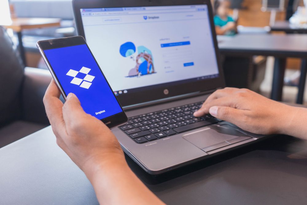 The Dropbox logo and website displayed on a smartphone and laptop, respectively